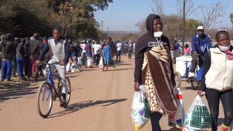 AFRICA,SOUTH AFRICA,CIRCA 2020. Poor and unemployed people walking back to their informal settlement with food parcels they received from the NGO, The Gift of the Givers, during the Covid-19 pandemic