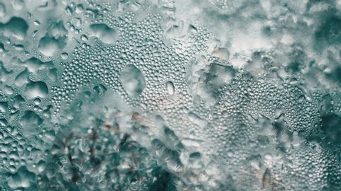 condensed water on glass in slow motion and macro, water bubbles on glass, close up