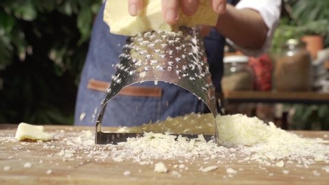 chef grating hard cheese in an outdoor kitchen 