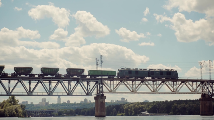 Cargo Train Moving On Railroad Bridge. Kiev City Bridge. Freight Train Passing Railroad Delivery. Electric Locomotive With Wagons Rides On Steel Railway. Heavy Container Industry Train Transportation 
