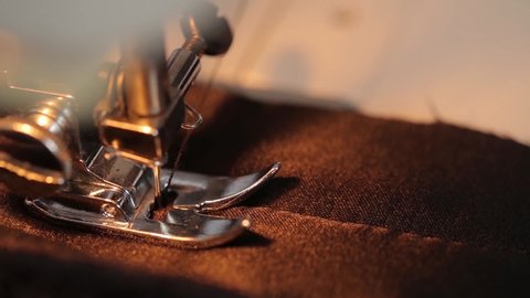 Sewing Machine Needle in Motion. Close-up of sewing machine needle rapidly moves up and down. The tailor sews black fabric on the sewing workshop. The process of sewing fabric. Part1