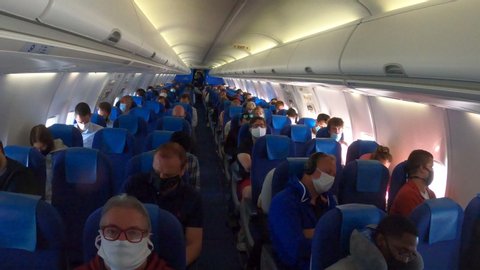 AMSTERDAM, NETHERLANDS - JUNE 2020: Airline passengers wear protective face masks inside KLM airplane due to Covid-19 coronavirus regulation, international air travel during pandemic