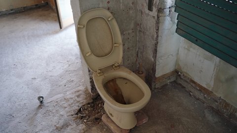 Sanitary and hygiene concept, old dirty rusty toilet in abandoned ancient house construction, clogged wc with bacteria and microbe, no flushing water inside the vintage damaged toilet. Repairing works