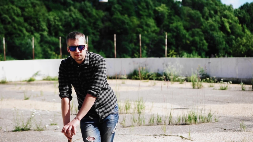 The guy is leaning on a baseball bat and looking forward, taking off his glasses. Frames in motion.