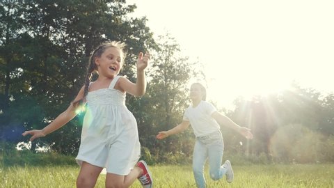 children kid dream together run in the park at sunset. happy family people in the park concept. two sisters playing catch-up run. baby child fun running in green meadow. happy family kid dream concept