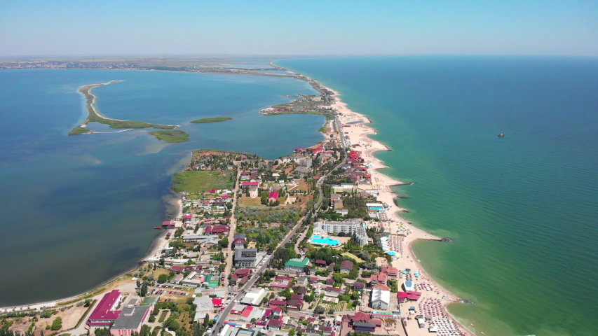 Aerial drone footage Seaside resort by the sea. Beautiful sandy beach on Berdyansk sea spit, Sea of ​​Azov. Buildings are located along the entire length of the sea coast
