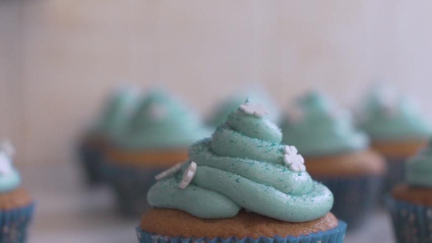 Close up slide shot of bunch of cupcakes, with blue icing on top