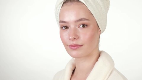 Beautiful tender young girl in a white towel and home bathrobe with clean fresh skin posing in front of the camera. Beauty face. Skin care. Photo taken in studio on a white isolate background.