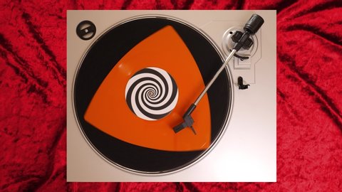 Orange shaped vinyl record on a DJ turntable with red velvet background. Circular long player shot from above. Party, disco, punk, grunge, pop in 60s, 70s, 80s, 90s 4K