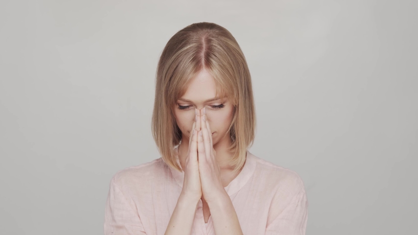 Sad and depressive young woman over grey background.