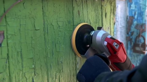 Close-up of a man grinding an old wooden surface with an orbital sander. Renovation of an old house.