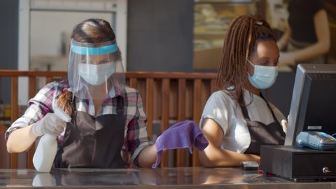 Portrait attractive waitress wear face mask and face shield cleaning counter with disinfector and wet wipe before welcome customer. New normal hygiene restaurant concept.