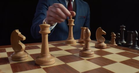 Close up of player making castling move with pieces playing chess isolated on black background. Businessman playing with wooden king and rook. Ideas competition and strategy concept