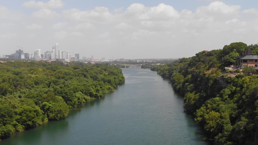High drone shot of ladybird lake and the cliffs. Shows a home with the view of downtown Austin on the horizon. Royalty-Free Stock Footage #1056569927