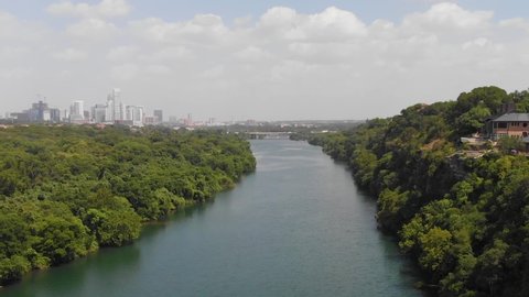 High drone shot of ladybird lake and the cliffs. Shows a home with the view of downtown Austin on the horizon.