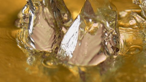 Boiling liquid gold with ice cubes. Elegant slow-motion footage of a high-end drink in extreme close-up