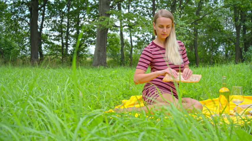 Woman relaxing outdoors, preparing appetizer to picnic at summer time