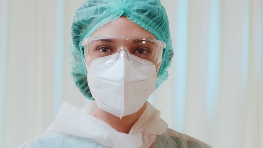 Woman frontline medical key worker with hazmat suit and protective face mask KN95 takes off her medical glasses, her hands are in rubber gloves. Coronavirus COVID-19 disease global pandemic outbreak Royalty-Free Stock Footage #1056574994