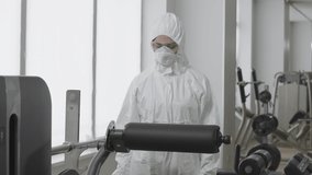 Portrait of concentrated woman in protective suit cleaning equipment with antiseptic sanitizer. Confident female employee preparing gym for visitors on Covid-19 pandemic. Coronavirus lifestyle. - Powered by Shutterstock - Get 15% off with code: PIKWIZARD15
