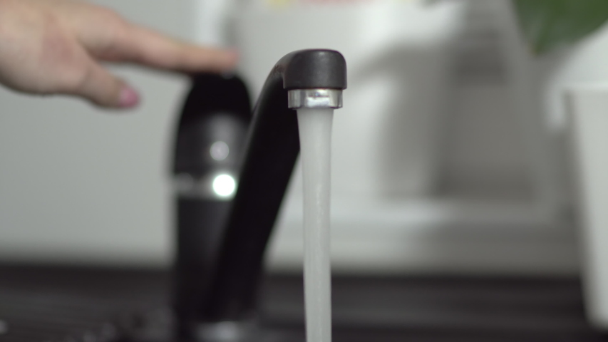 Hand turning modern black granitte tap on and off | Shutterstock HD Video #1056579401