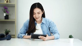 Happy young attractive asian woman using smartphone looking social media entertainment at home.