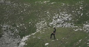 Tracking aerial shot of an isolated man playing guitare in the nature