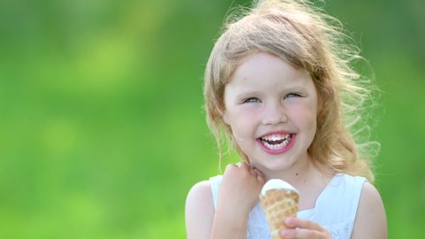 Little Cute Girl in White Summer Dress Enjoying Delicious Ice Cream. Kid with Ice Cream in the City Park. summer family lifestyle. Childhood