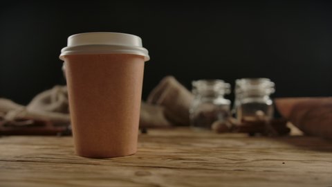 Two brown one-off paper cups for hot beverages with copy space. Hot drinks, coffee, tea for take away. Indoors, wood shelf. Concept for special offer or promo. Dolly shot with zooming