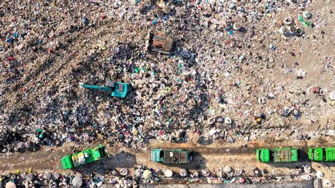 Time lapse of Aerial top view of A Huge Waste, garbage, dump, rubbish landfill. A landfill compactor, group of workers sort out the garbage in the landfill. Trash trucks dump waste polluting products.