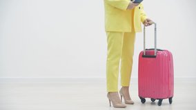 Cropped slowmotion video of female carrying a suitcase and passport over white background with copyspace.