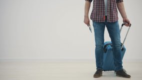 Cropped video of happy young man ready for the trip with his suitcase packed over white background.