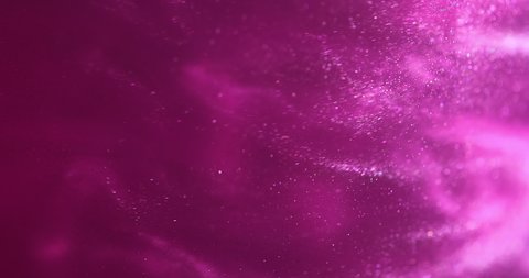 Pink glittery paint creating abstract clouds. Art backgrounds. Fuchsia color fluid is swirling in beautiful silver clouds. Glitter dust is moving slowly in water. Amazing abstract texture background
