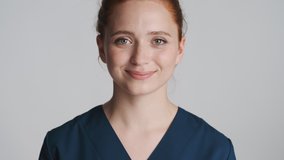 Young beautiful smiling nurse happily looking in camera over white background. Happy expression