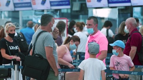 Many masked people moving in line airport. Passing border control airport. Respiratory protection tourist in public place, traveling. COVID-19 viral infection quarantine. CZ, Prague Airport, 24.7.2020