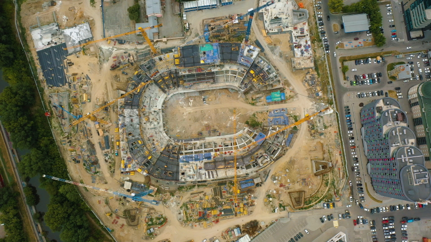 Ice arena building under construction, located in Russia Yekaterinburg, top view. Aerial: tower cranes works on construction site of sports complex, ice palace. Materials, equipment, machinery works