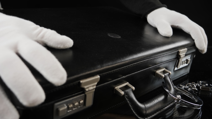 Man in white gloves opens a briefcase full of gold bars. Handcuffed case with fine gold bars. Shiny gold bars in close-up view, 4K resolution Royalty-Free Stock Footage #1056604358
