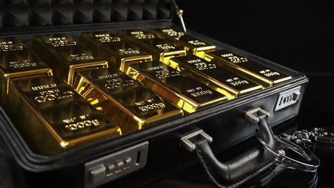 Man in white gloves opens a briefcase full of gold bars. Handcuffed case with fine gold bars. Shiny gold bars in close-up view, 4K resolution