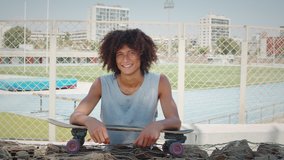 Hispanic latin young man holding skateboard and smiling, portrait of happy skater in skatepark spain, barcelona, brazilian male professional skateboarder - Powered by Shutterstock - Get 15% off with code: PIKWIZARD15