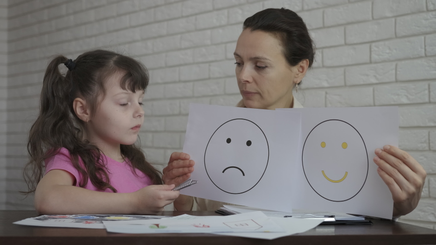 The mood of the child at the psychologist. Female psychologist shows drawings with mood. Royalty-Free Stock Footage #1056607841