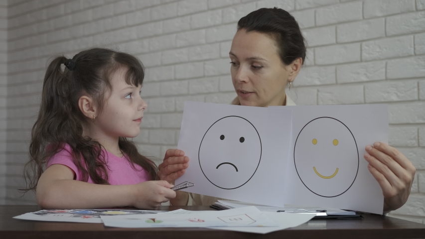 The mood of the child at the psychologist. Female psychologist shows drawings with mood. | Shutterstock HD Video #1056607841