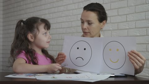 The mood of the child at the psychologist. Female psychologist shows drawings with mood.
