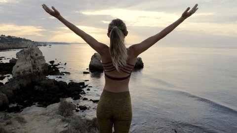 Happy young woman arms outstretched on the beach at sunset embracing life, healing and freedom concept 