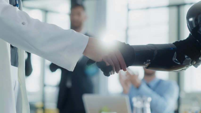Businesswoman and prototype robot shaking hands agree to cooperation. Corporate business people interacting with artificial intelligence. Close-up.