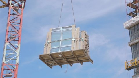 Work at home construction. The crane lifts double-glazed windows. A crane raises windows for installation in a residential building.