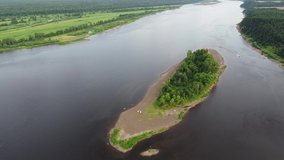 Aerial video filming overlooking the Kama river and a wonderful green island with a deciduous forest, a beach, and tourist tents. Golyany village, Udmurt Republic, Russia. Active rest on the river.