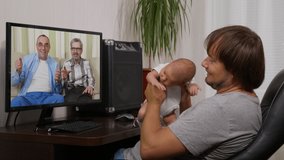 man with infantat home having video chat on PC, interacting together online during social distancing and self isolation in quarantine lockdown.