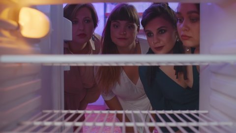 Four beautiful plus size ladies opening empty fridge feeling hungry and upset. Overweight girlfriends looking into empty refrigerator looking for food. Body positive and diet concept