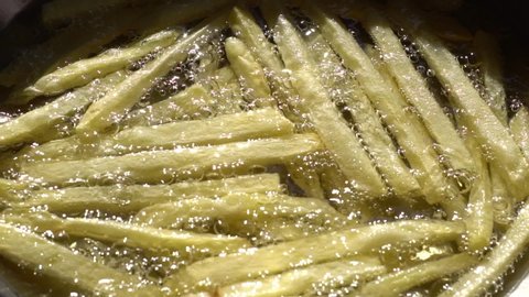French fries. Finger chips. Close up. Slow motion.
Frying and stirring potato strips in hot sunflower oil.