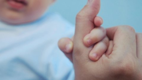 baby newborn holding a mom hand. kid dream concept. close-up baby hand grabs the finger of the mother hand. newborn baby and mom hands. mother taking care of her kid son happy family dream of health