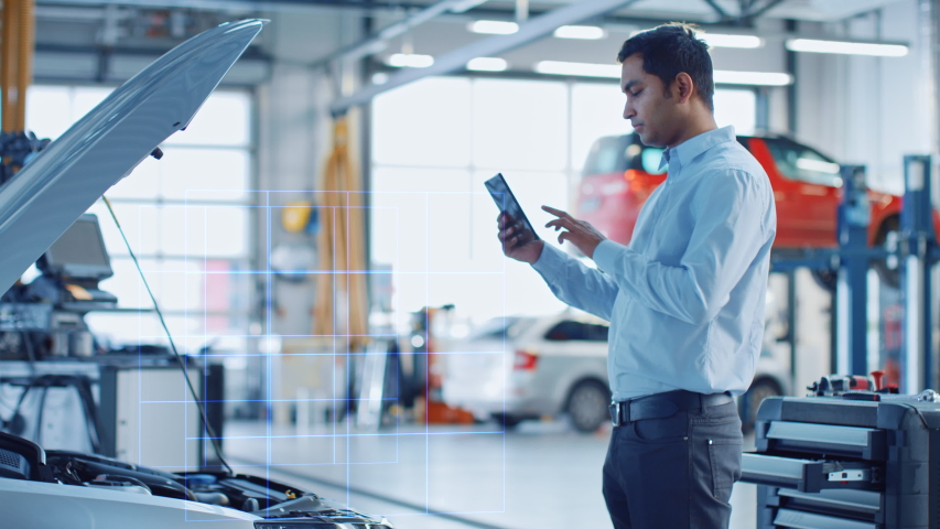 Car Service Manager Uses a Tablet Computer with a Futuristic Augmented Reality Diagnostics Software. Specialist Inspecting the V6 Internal Combustion Engine in Order to Find Broken Components. Royalty-Free Stock Footage #1056636917